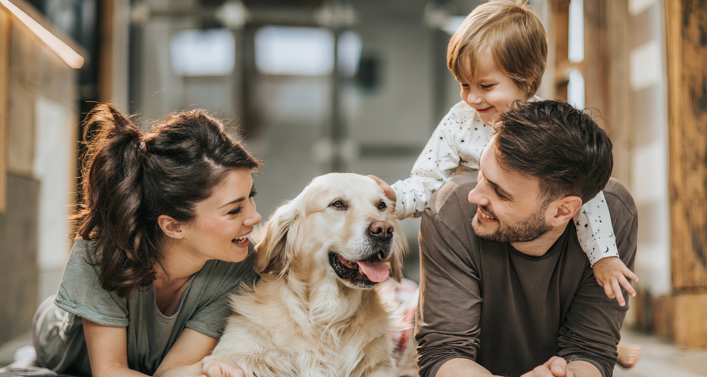 A family of four sits on the floor with a dog, enjoying a relaxed moment together in a cozy living room.